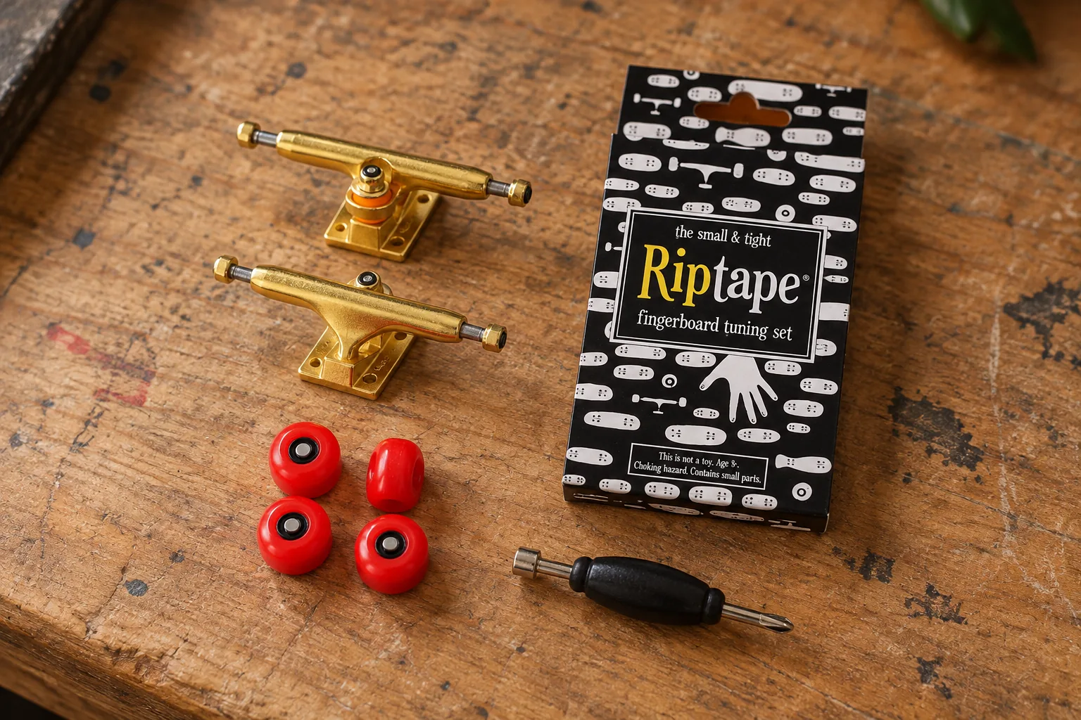 Ejes Blackriver Wide 2.0 dorados, ruedas Bollie Pro Wheels rojas, caja de Riptape y herramienta Bollie sobre un banco de trabajo